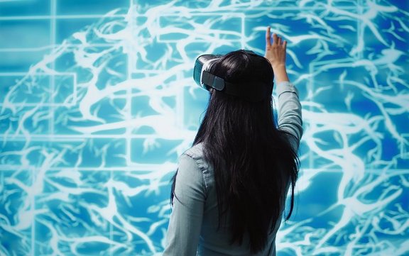Developer wearing VR headset looking at artificial intelligence hologram Entwickler mit VR-Headset schaut sich ein Hologramm der künstlichen Intelligenz an